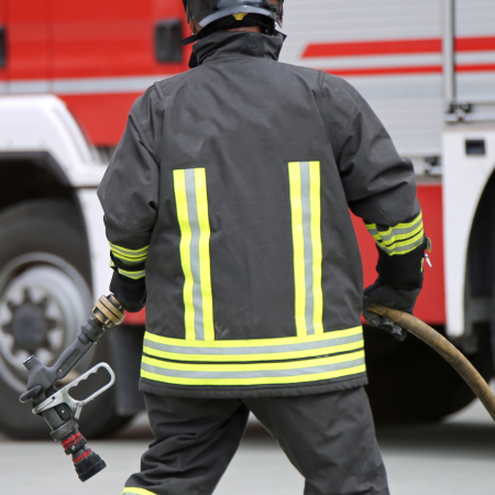 ugniagesys stovi prie gaisrinės mašinos